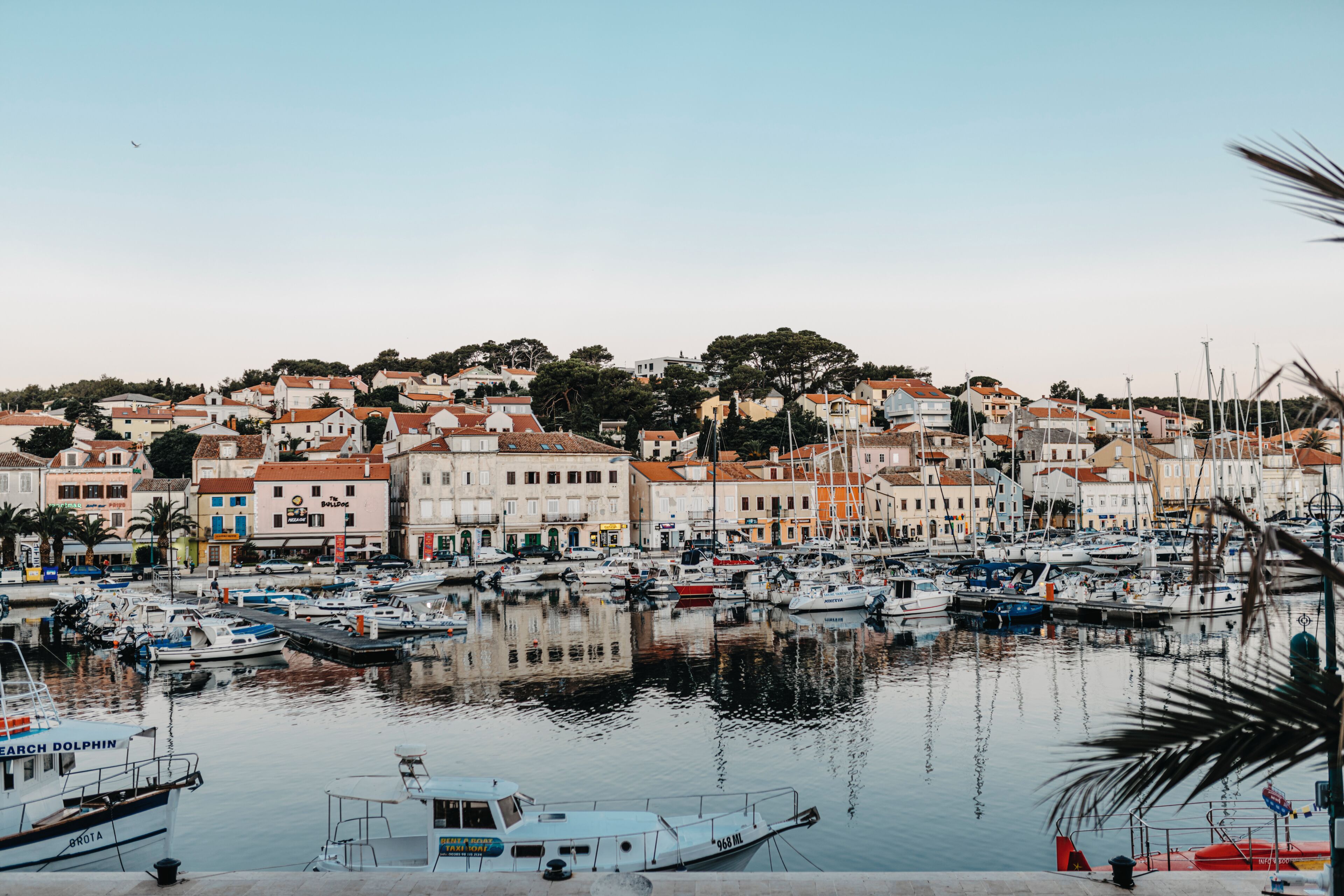 Uma marina com barcos atracados, rodeada por edifícios com telhados em tijolos vermelhos.