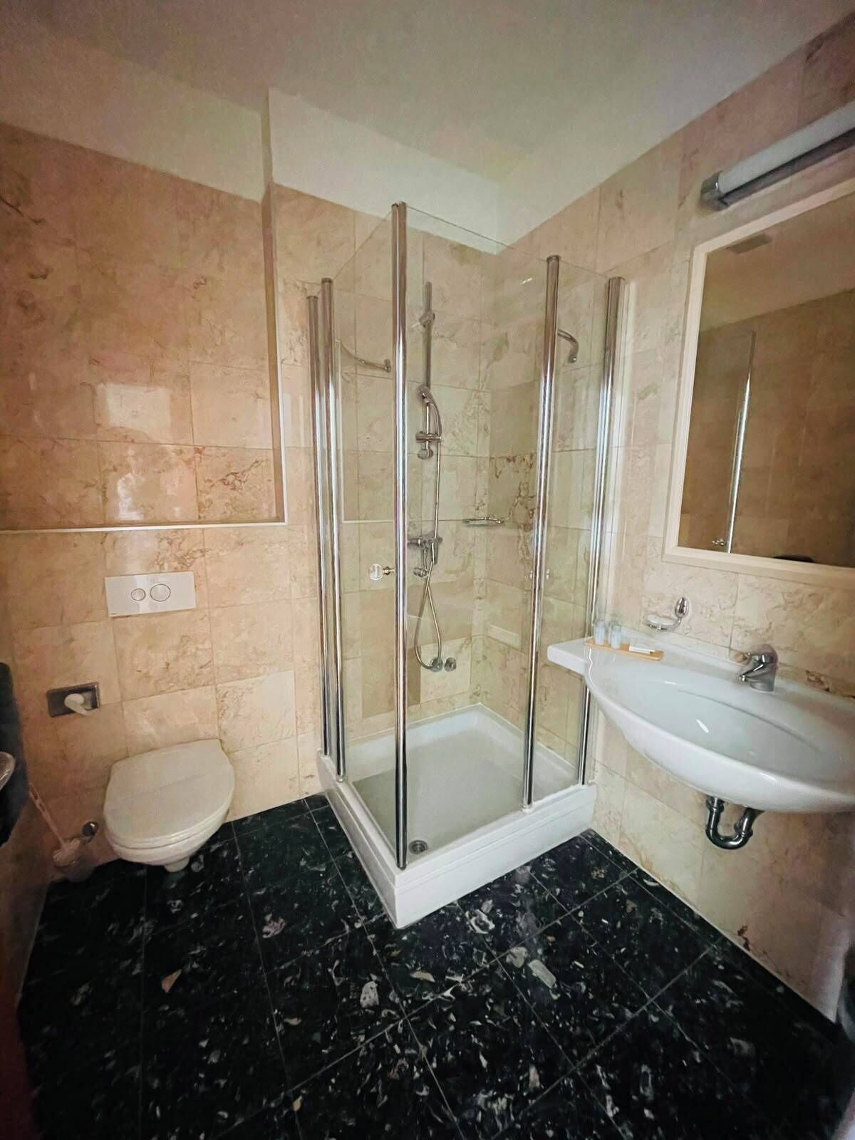 A bathroom with a glass-enclosed shower, a toilet, and a sink.