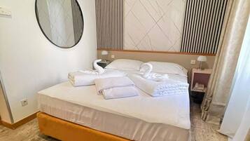 Una habitación de hotel con cama, espejo redondo, pared con diseño geométrico y mesita de noche con lámpara.