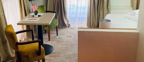 Una habitación de hotel con cama, escritorio, silla, televisor y cortinas.