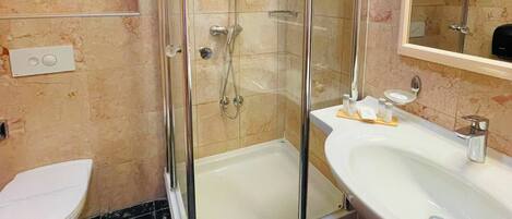 A modern bathroom with a glass-enclosed shower, a white sink, and a mirror.