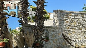 Un jardín con palmeras, una hamaca y un muro de piedra.