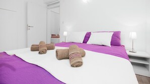 Una habitación de hotel con cama, almohadas, una mesita de noche y toallas.