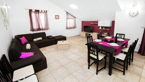 Un espacio habitable compacto con sofá, mesa de comedor, sillas y televisor.