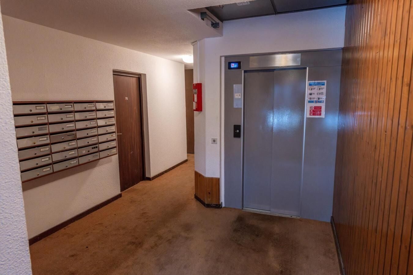 A hallway with a row of mailboxes, a door, and an elevator.