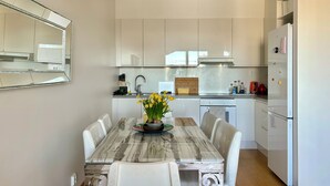 Une cuisine moderne avec des meubles blancs, une table à manger en marbre et un lustre.