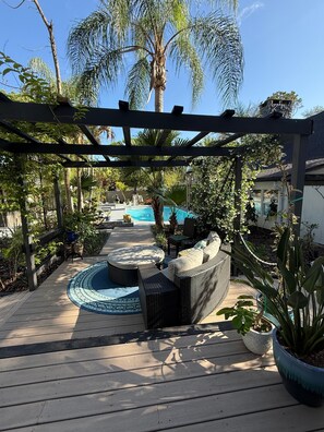 A wooden deck with a pool, outdoor seating, and lush greenery. - Charming Private Cottage with Resort-Style Pool Near Tampa Attractions (Tampa)