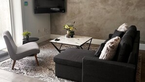 Ett modernt vardagsrum med en soffa, en fåtölj och en tv som är monterad på väggen.