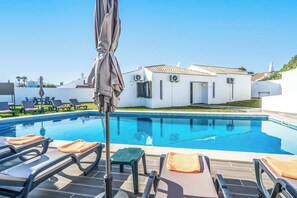 A swimming pool with lounge chairs and umbrellas, a white building with a tiled roof, and a clear blue sky. - Villa Oura - Four Bedroom Villa, Sleeps 8 (Albufeira)