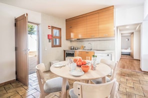 A compact kitchen with wooden cabinets, a dining table with chairs, and a small window. - Villa Oura - Four Bedroom Villa, Sleeps 8 (Albufeira)
