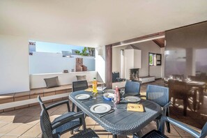 An outdoor dining area with a table set for four, surrounded by chairs, and a view of a building with a staircase. - Villa Oura - Four Bedroom Villa, Sleeps 8 (Albufeira)