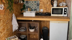 Een kleine keuken met een houten spatwand, een magnetron, een spoelbak en een kleine koelkast.