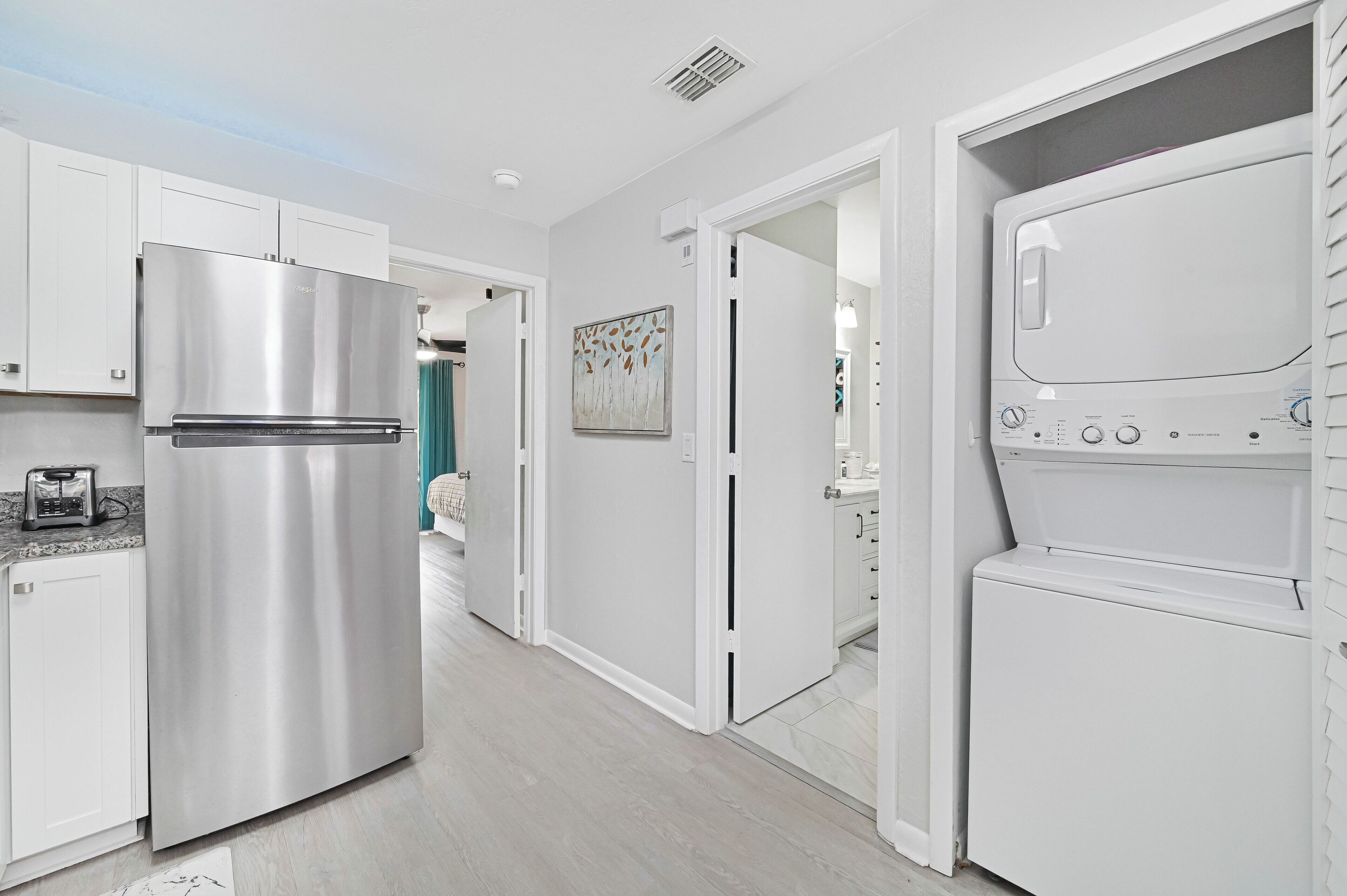 Una cocina moderna con armarios blancos, un refrigerador de acero inoxidable y un horno empotrado.