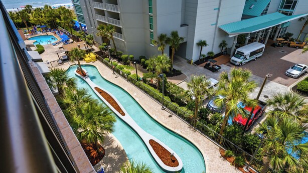 Un hotel con zona de piscina, aparcamiento y vistas al océano.