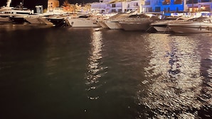 A marina at night with boats docked, a hotel named 'BENABOLA' with a sign, and a building with 'HOTEL' and 'SKYLOUNGE' signs. - Penthouse in Puerto Banús (Marbella)