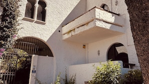 A building with a stone facade, arched windows, and a staircase leading to a door. - Penthouse in Puerto Banús (Marbella)