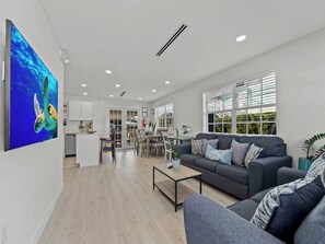 A spacious living area with a grey sofa, a coffee table, and a dining area with chairs and a table. - The Perfect Hideaway Retreat for Your FLKeys Getaway (Marathon)