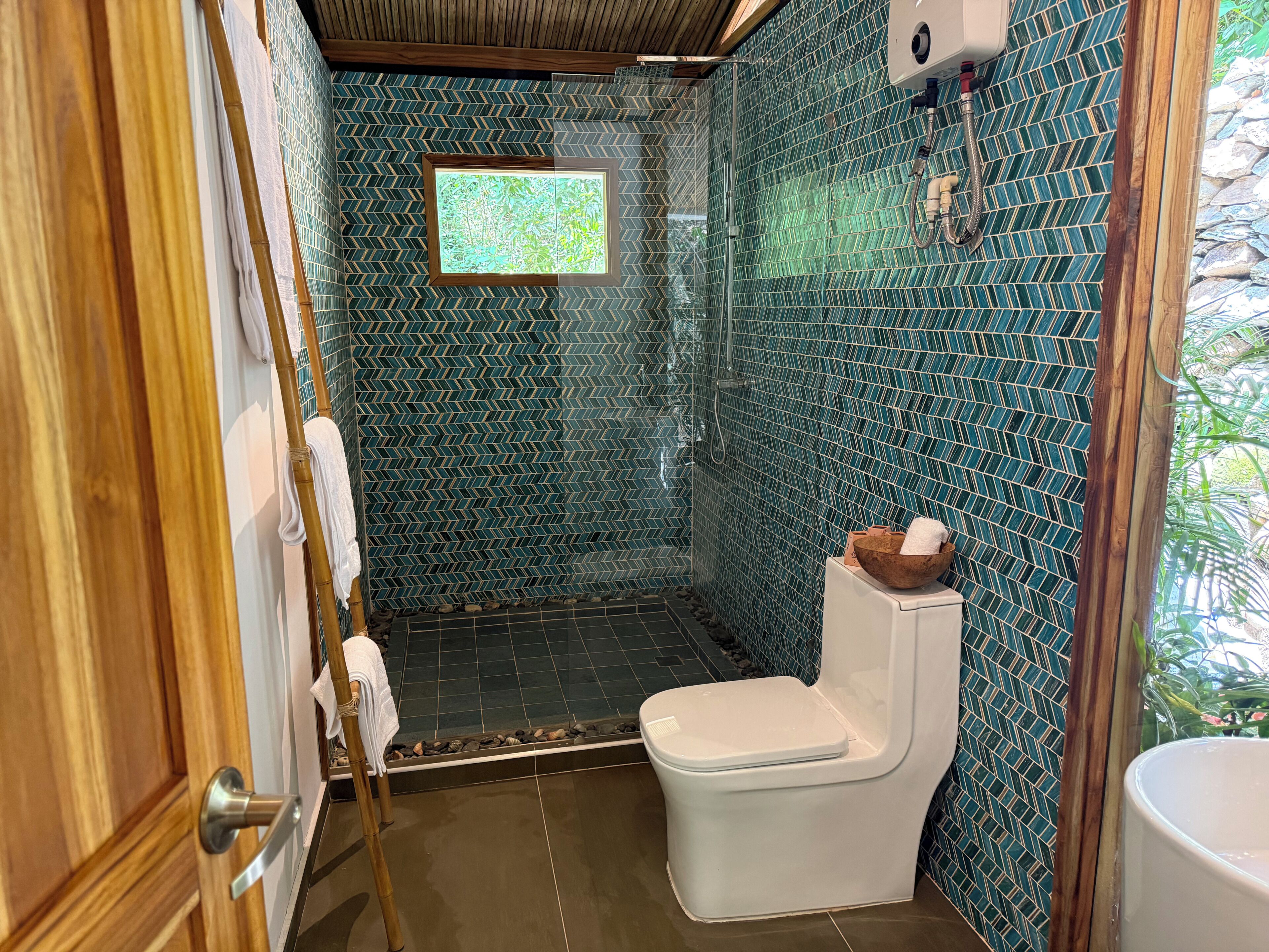 Un baño con ducha, inodoro y ventana.