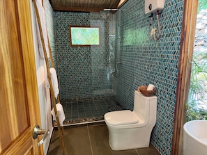 Un baño con ducha, inodoro y ventana.