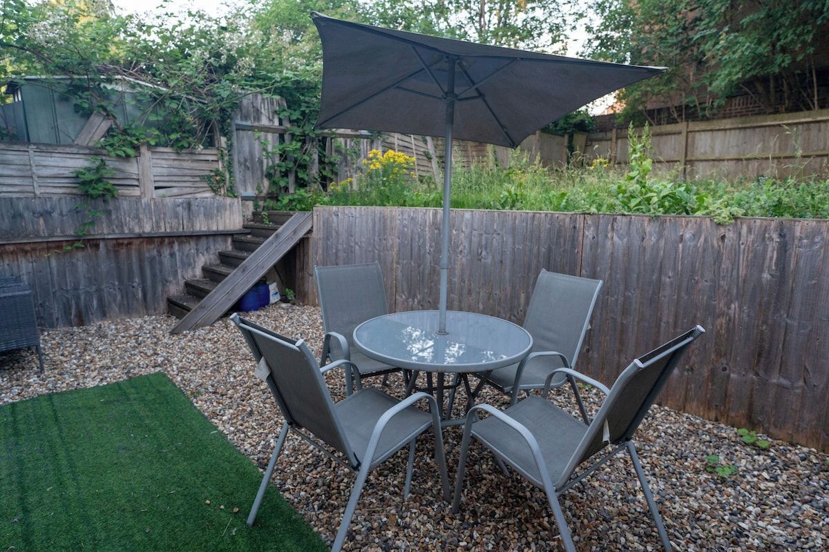 A patio with a round table and chairs, an umbrella, and a wooden fence.