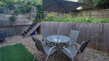 A patio with a round table and chairs, an umbrella, and a wooden fence.