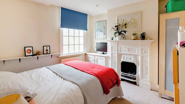 A bedroom with a bed, a television, a fireplace, and a window with a blue blind. - Room-double Bedroom With own Bathroom in (London)