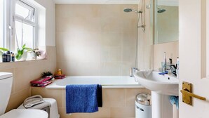 A bathroom with a bathtub, a sink, a toilet, and a trash bin. - Room-double Bedroom With own Bathroom in (London)