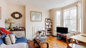 A living room with a sofa, a coffee table, a bookshelf, a television, and a dining area. - Room-double Bedroom With own Bathroom in (London)
