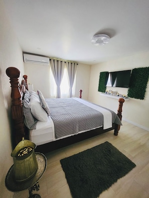 Ein Schlafzimmer mit einem Bett, Vorhängen, einem Fernseher und einem kleinen Regal.