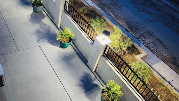 A rooftop terrace with potted plants, a railing, and a street view. - Jaden's Guest House - by Zenbreak (Cane Garden)