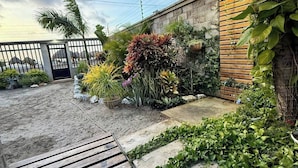 A wooden deck, a concrete pathway, and a variety of plants and shrubs. - Luxury Beachfront House Steps From the Sea (Puerto Colombia)