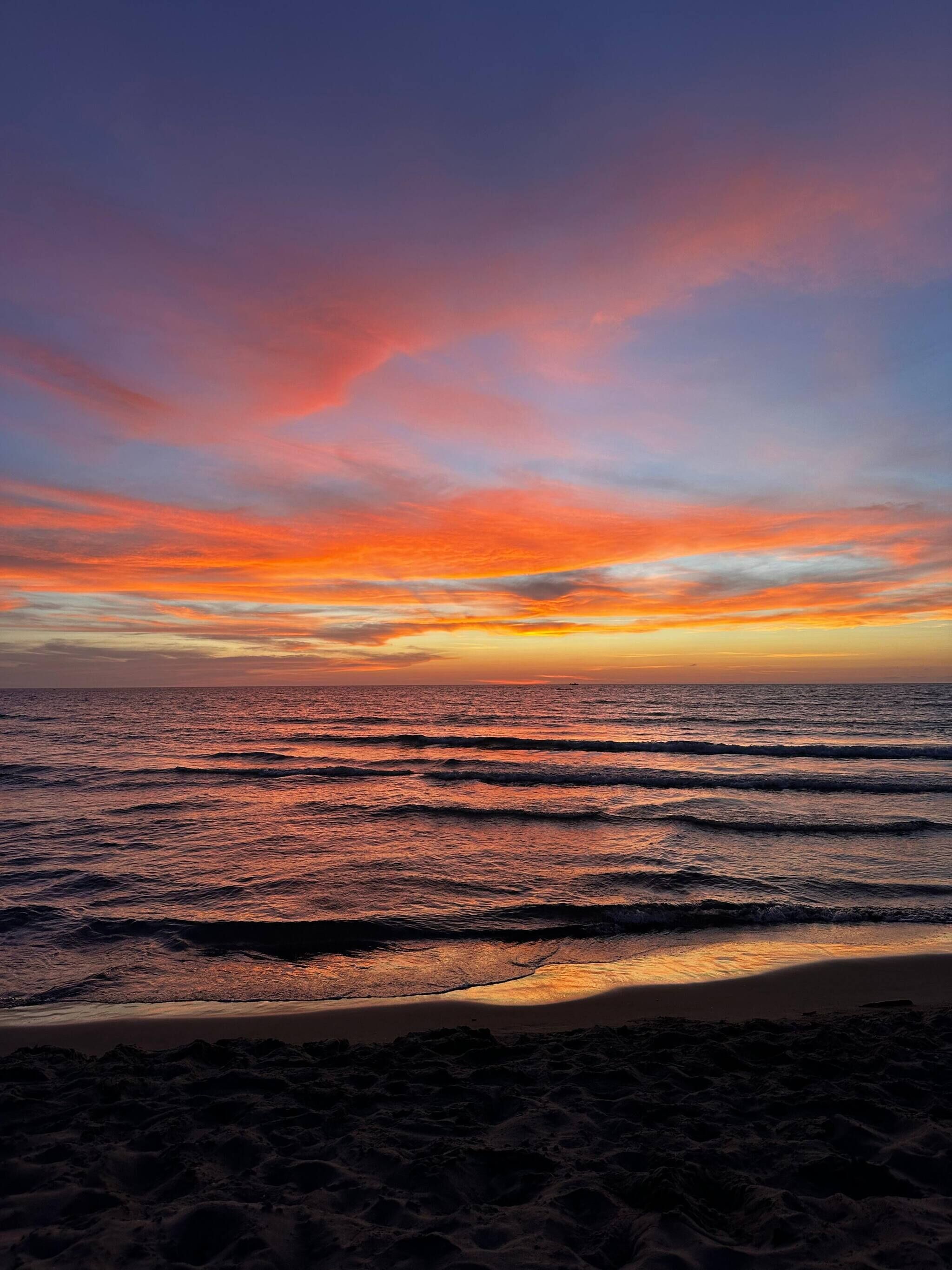 Une plage avec des vagues et un coucher de soleil.