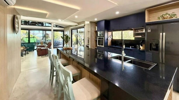 A modern kitchen with a central island, built-in appliances, and a dining area with chairs. - Luxury Beachfront House Steps From the Sea (Puerto Colombia)