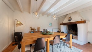 Ein Essbereich mit Holztisch, schwarzen Stühlen, Pendelleuchten, einem Kamin und rustikalem Dekor.