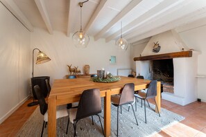 A dining area with a wooden table, black chairs, pendant lights, a fireplace, and a rustic decor. - Grand'maison - Avec piscine privée (Bouquet)