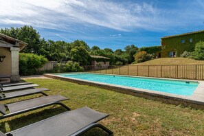 A swimming pool with lounge chairs, a grassy area, and a building with a tiled roof. - Grand'maison - Avec piscine privée (Bouquet)