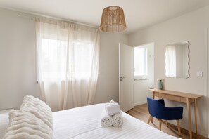 A hotel room with a bed, a desk, a chair, a hanging light fixture, a door, and a mirror. - Casa Fiorenza - À 750 mètres de la plage (Dinard)