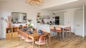 A modern kitchen with a dining area, wooden flooring, and a large mirror. - Casa Fiorenza - À 750 mètres de la plage (Dinard)