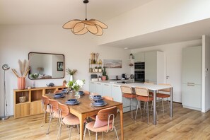 A modern kitchen with a dining area, wooden flooring, and a large mirror. - Casa Fiorenza - À 750 mètres de la plage (Dinard)