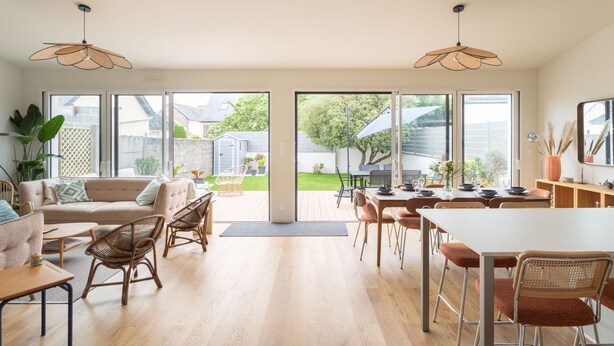 A spacious living area with a sofa, dining table, and chairs, large windows, and a view of the backyard. - Casa Fiorenza - À 750 mètres de la plage (Dinard)
