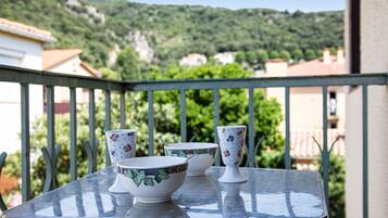 A balcony with a metal table, three bowls, and a cup.