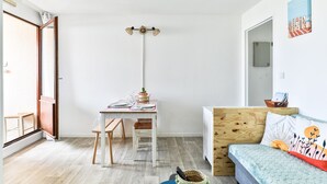 Ein Zimmer mit Holzschreibtisch, Stuhl, Bett mit Kopfteil, Wandleuchte und Fenster mit Aussicht.