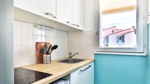 Eine Küche mit Fenster, Spüle, einer Holz Arbeitsplatte und einem Geschirrspüler.