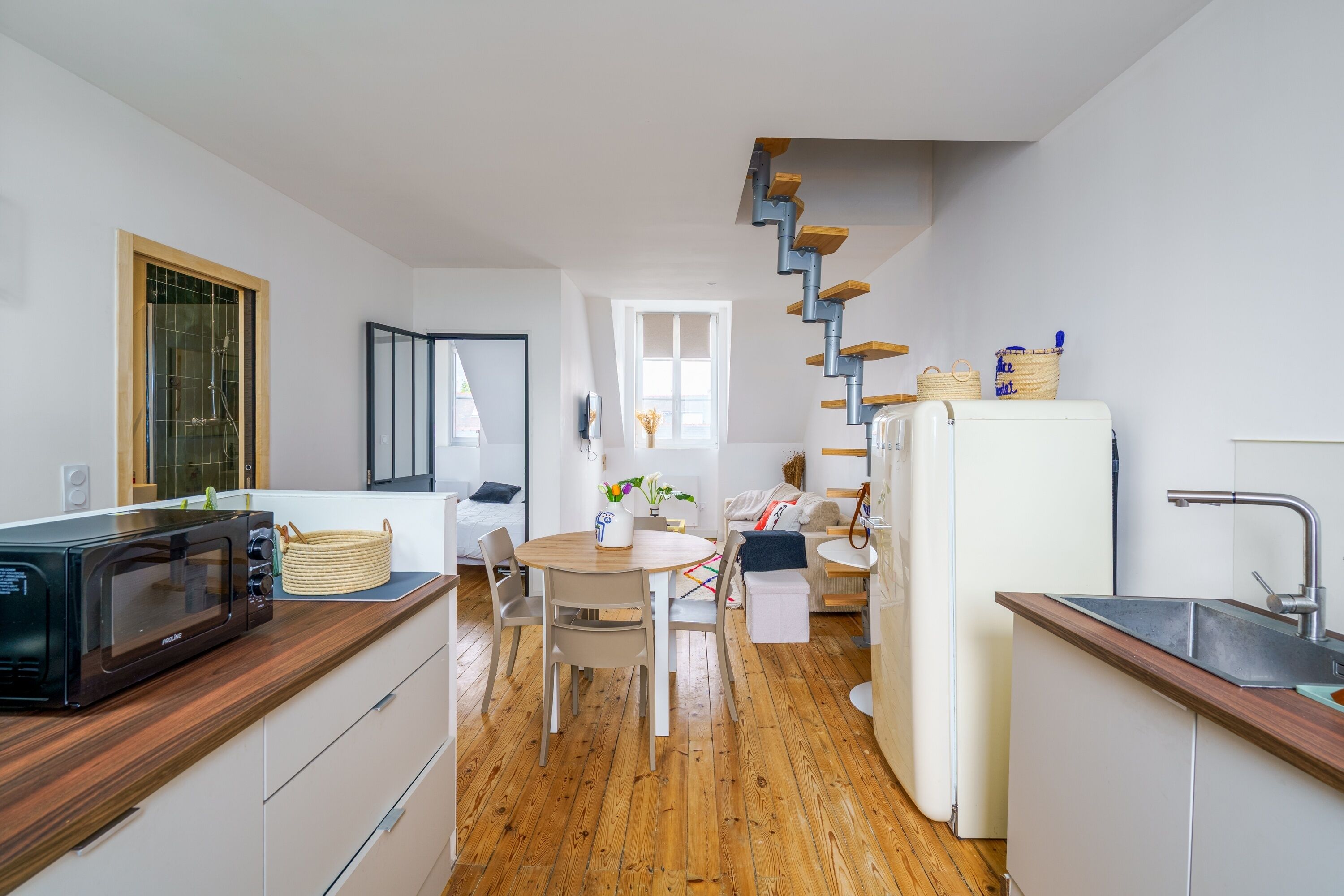 Een moderne keuken met een houten aanrecht, een magnetron, een spoelbak en een trap naar een ander niveau.