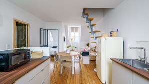 Eine moderne Küche mit einer Holzarbeitsplatte, einer Mikrowelle, einem Spülbecken und einer Treppe, die eine weitere Ebene hinaufführt.