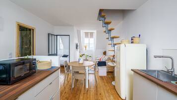Een moderne keuken met een houten aanrecht, een magnetron, een spoelbak en een trap naar een ander niveau.