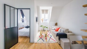 Ein modernes Zimmer mit Bett, einer Couch, einem kleinen Tisch und einem Fenster.