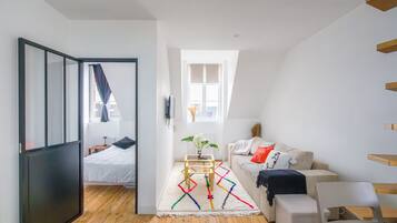 Een moderne kamer met een bed, een bank, een tafeltje en een raam.