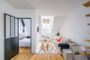 A modern room with a bed, a sofa, a small table, and a window. - Chez Alice - 200m de la Plage (Benodet)