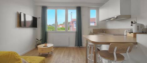 Una cocina moderna con comedor, un televisor en la pared y vistas al exterior.